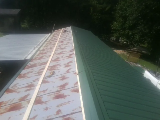 Old rusted panels beside newly installed green metal roofing — Wind Damage Roof Repair by Roofing Brothers in Hadlyme