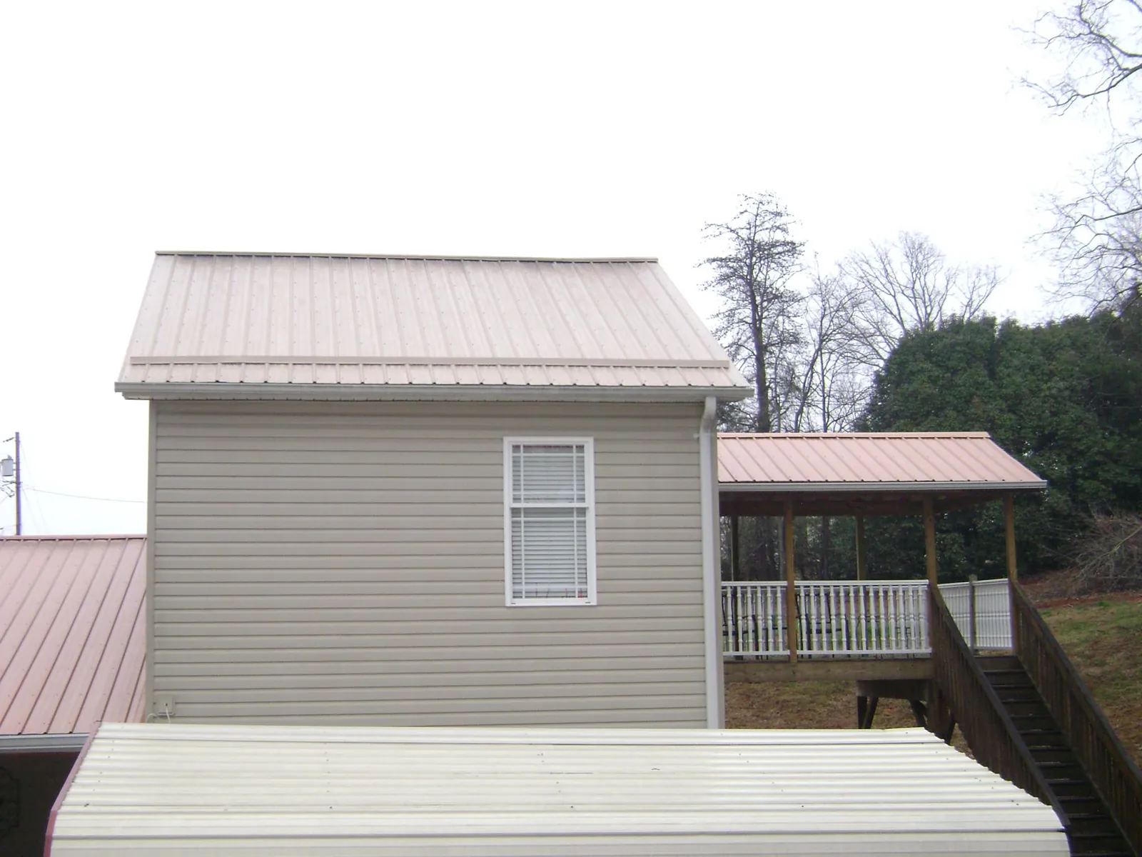 Tan metal roofs on a two story addition and attached porch, from a Roof Replacement job in Hadlyme