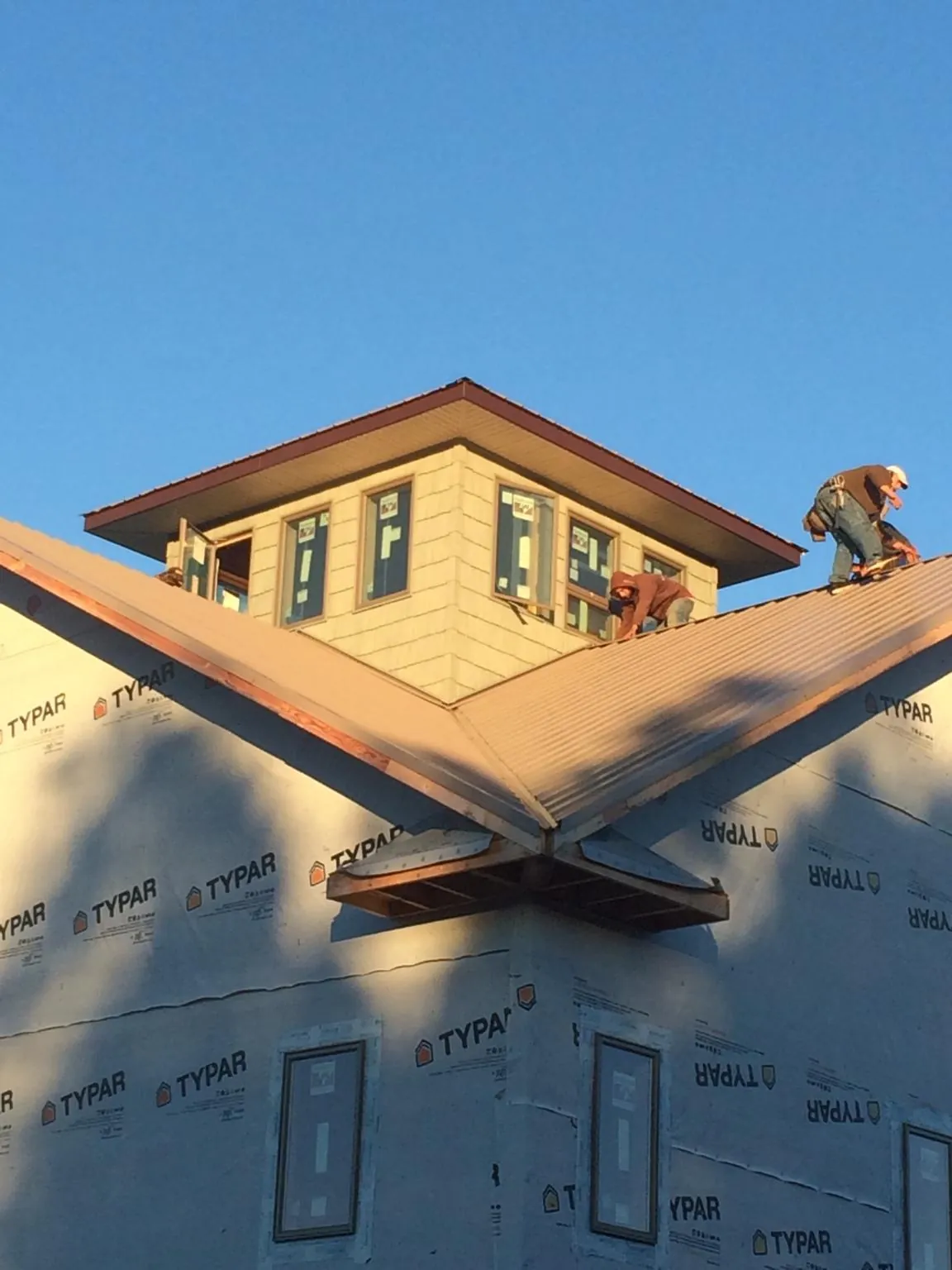 Roofers working around a rooftop cupola on a new metal roof at sunset — Roof Waterproofing in Hadlyme by Roofing Brothers